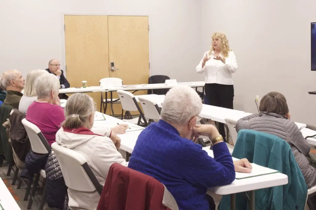 Woman in a white shirt is teaching older adults