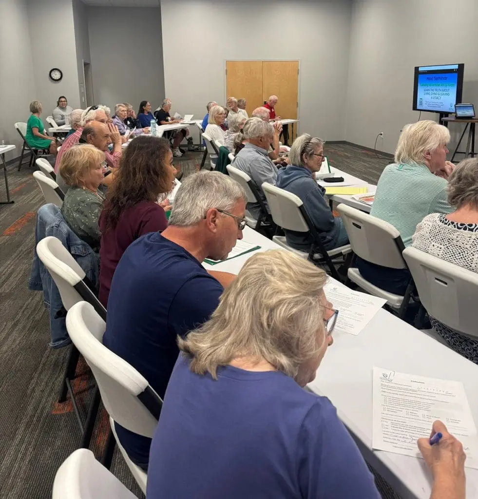 Older adults sitting at white tables doing worksheets