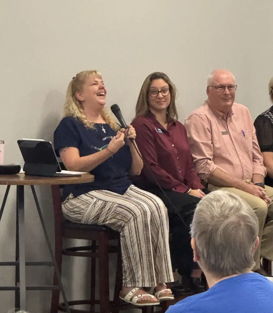 woman laughing into microphone at a senior education program